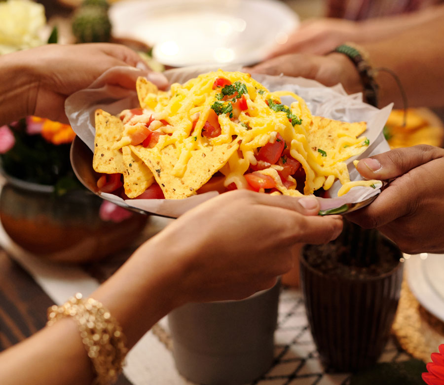 photo of people holding a plate of a tortilla chips dish